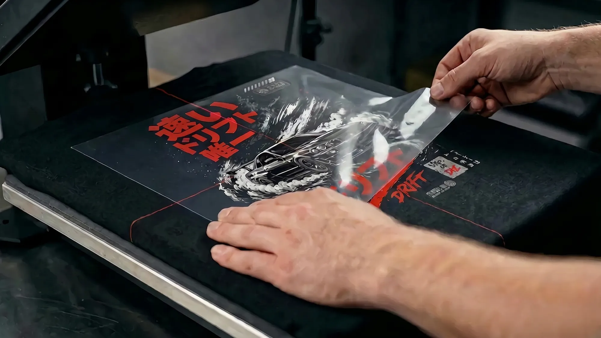 Les mains d'un artisan qui appliquent le design Street Drift sur un chandail dans l'atelier